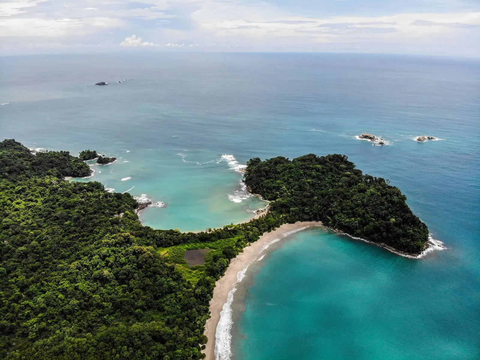 Aerial view of Punta Catedral, a forested headland joined to the coast by a strip of sand between two bays