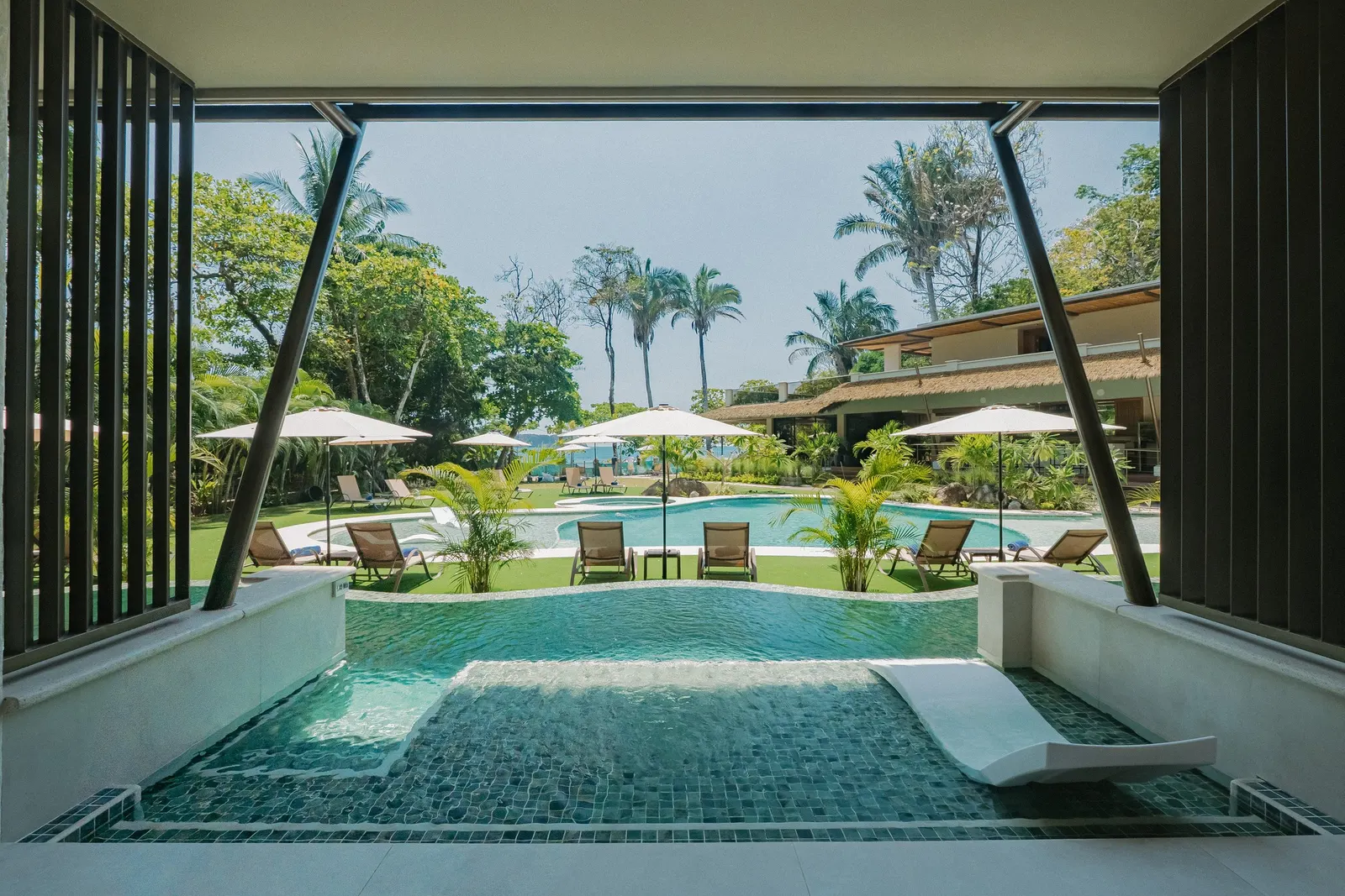 A Miamar water channel suite opening onto its own channel of water, with the pool and palms beyond